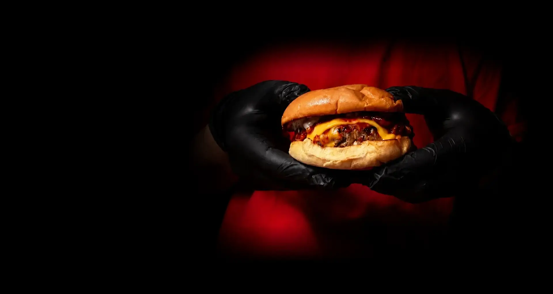 A5 Wagyu kimchi burger held in black gloved hands under a hard red key light at Alba Street, Social Distrikt, Dubai Mall Fountain Views