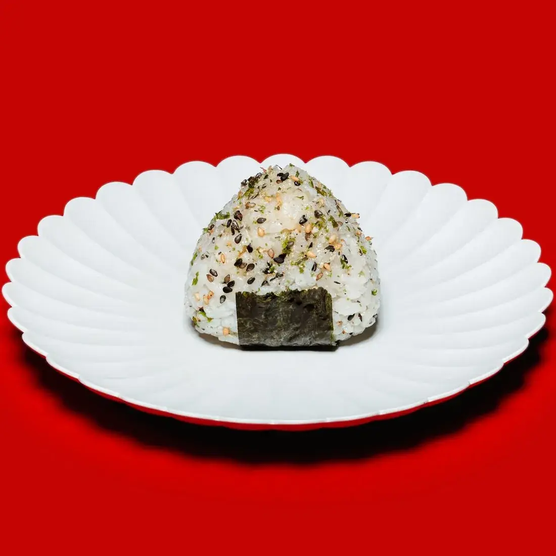 Salmon Onigiri on a fluted white plate against a red backdrop at Alba Street, Social Distrikt, Dubai Mall
